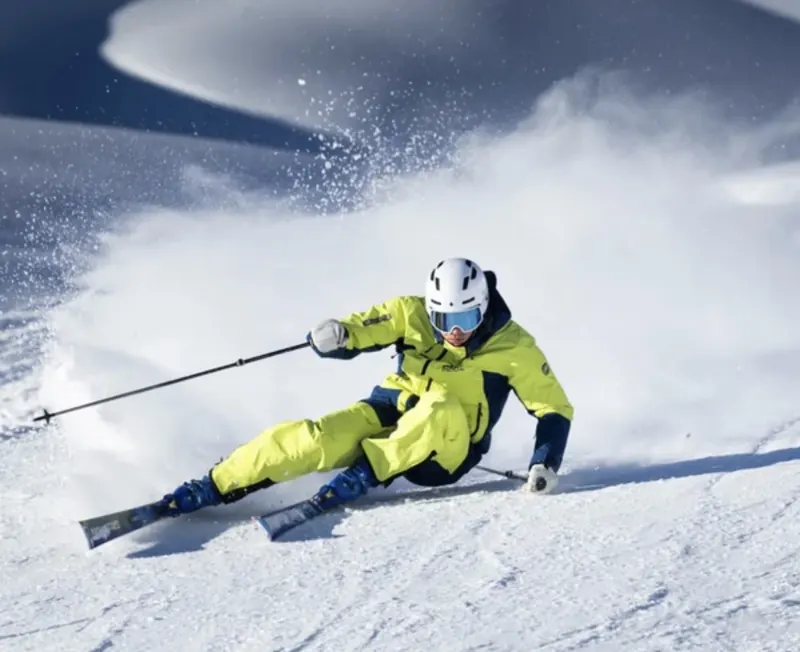 Skifahrer in gelber Jacke beim Carven auf der Piste